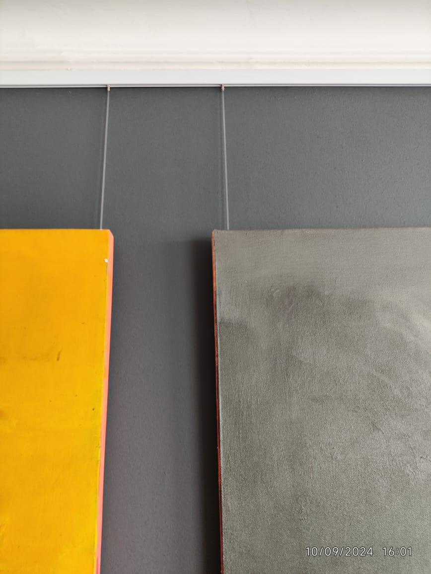 Adjustable gallery rail cables supporting two canvases