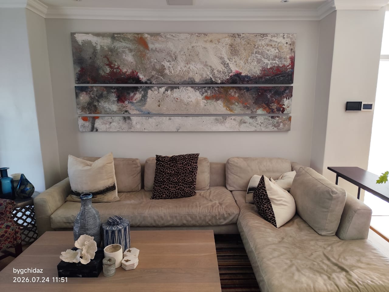 Three-panel abstract artwork professionally installed above a sectional sofa in Cape Town